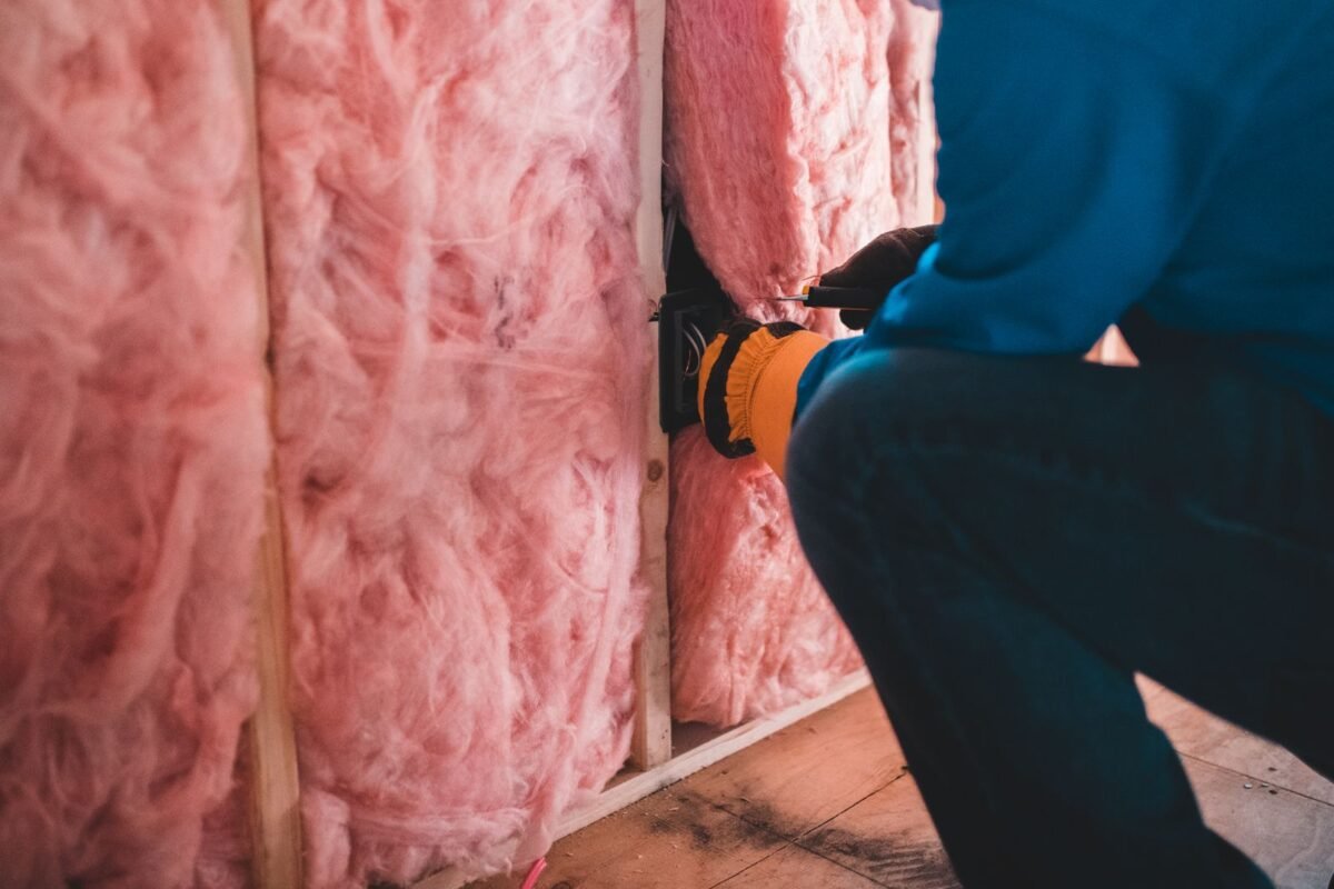 Worker in gloves fitting mineral wool insulation between wall studs